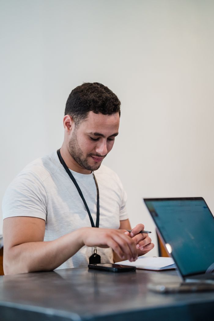 Young male office worker with laptop and notebook in a modern office setting.
